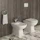 Weißes Bidet und WC von Ideal Standard, beide mit einer glatten Oberfläche. Handtuchhalter und moderne Wandverkleidung im Hintergrund. Boden in Marmoroptik.